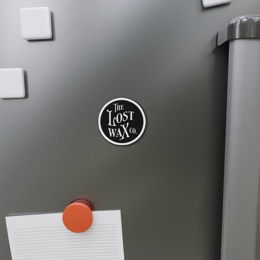 Round magnet with 'The Lost Wax Co.' logo on a refrigerator door.