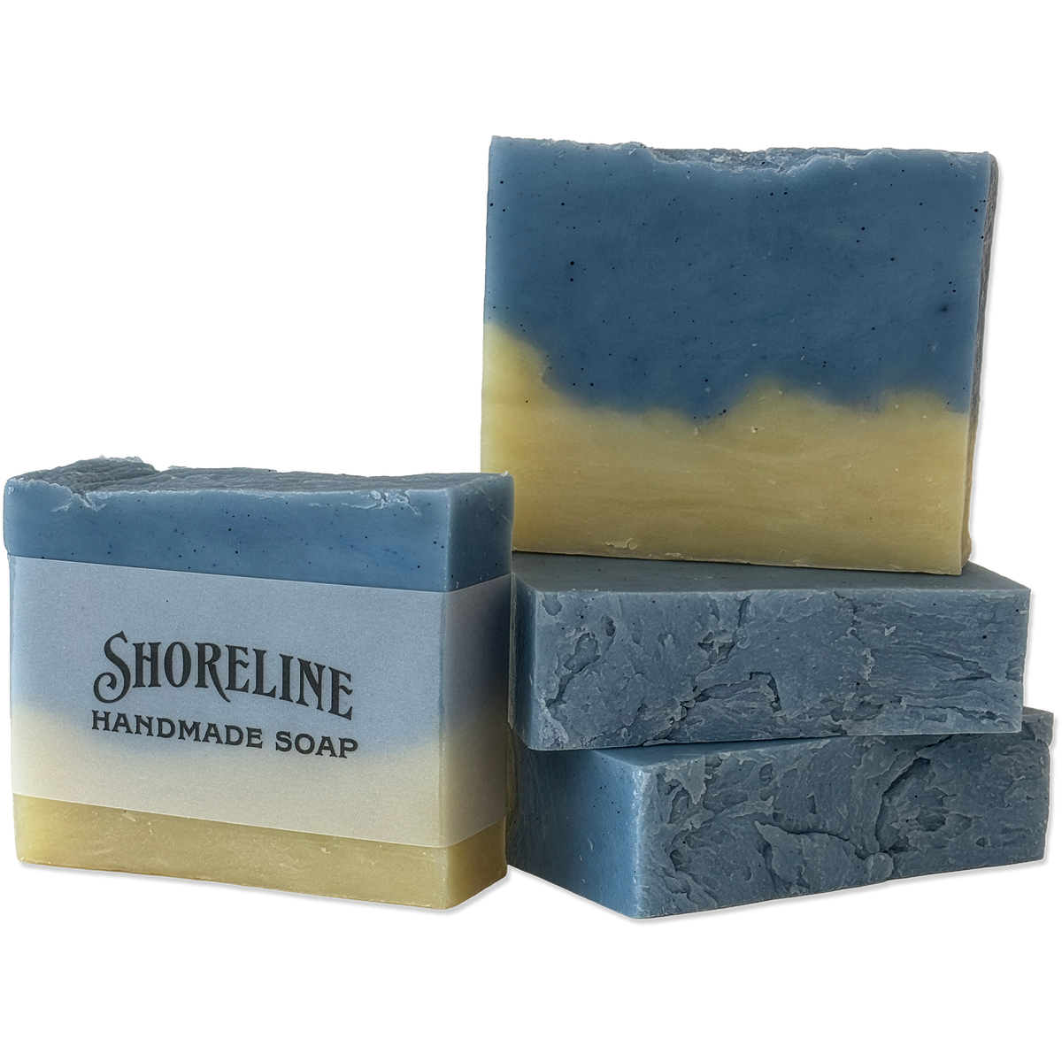 Four handmade soap bars with a blue and pale yellow marbled design, with one bar wrapped in a paper label that reads 'SHORELINE HANDMADE SOAP'.