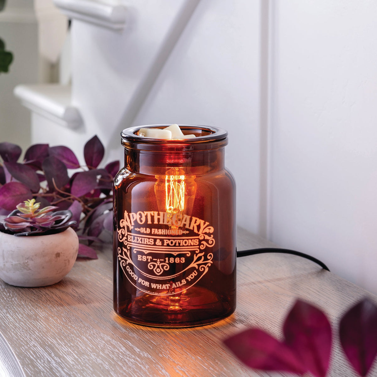 Amber glass apothecary-style jar wax warmer with Edison-style light bulb inside