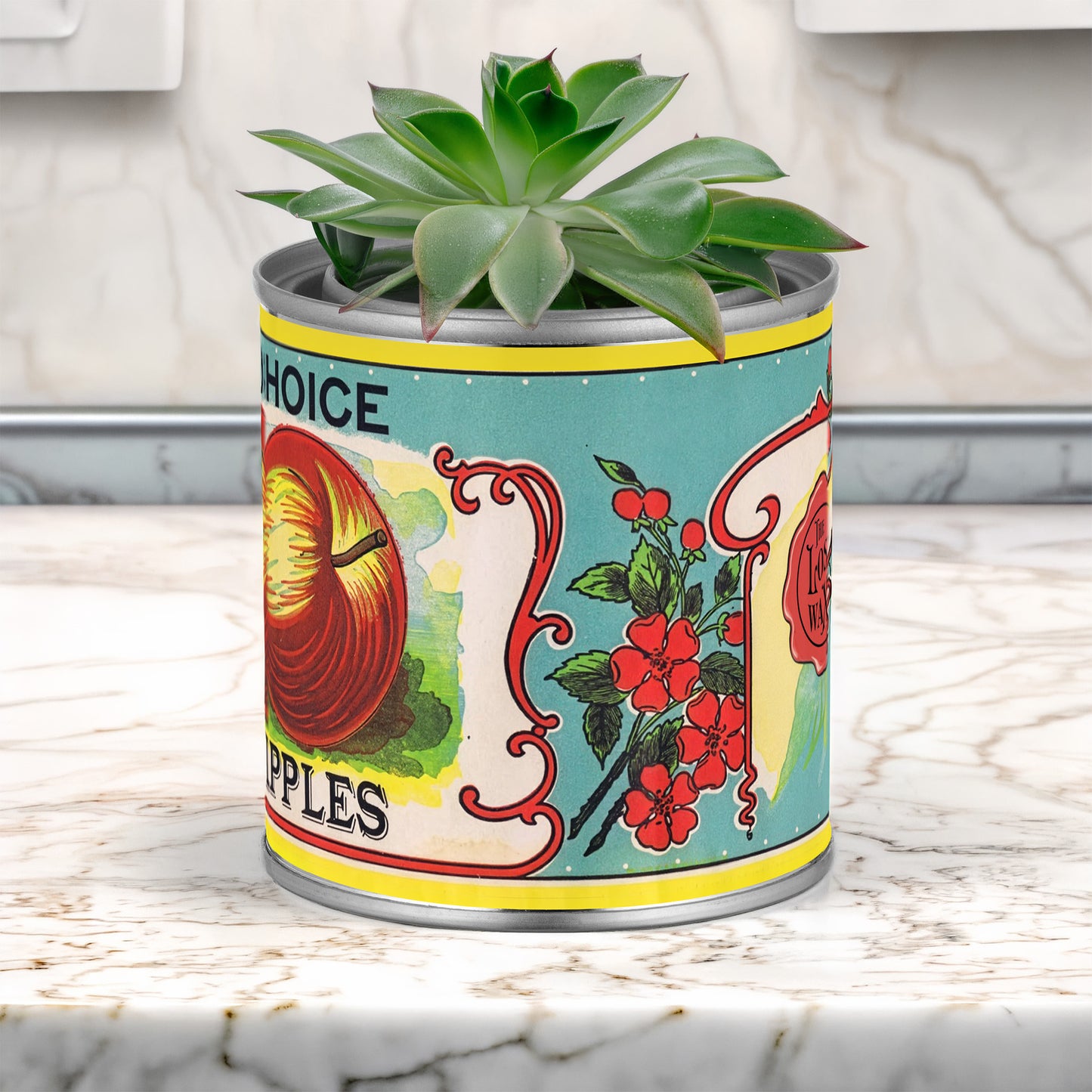 Potted plant in a decorative can with vintage apple label design on a marble surface.