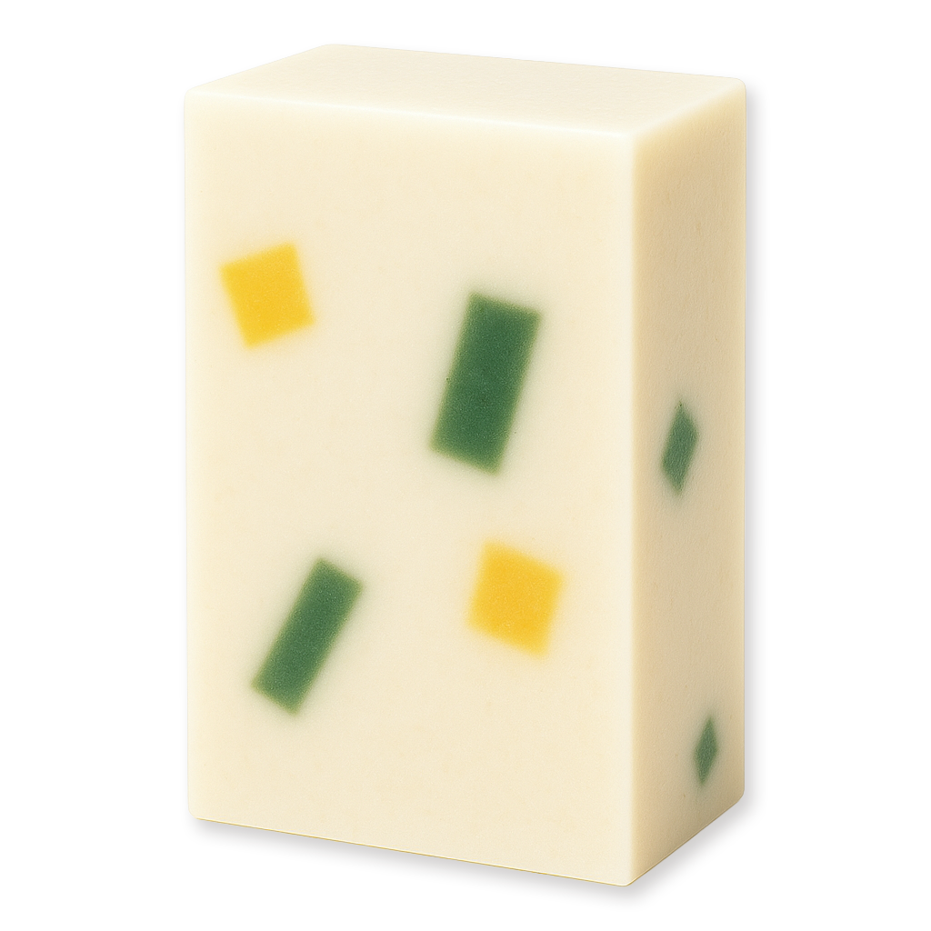 A rectangular bar of creamy off-white soap with embedded green and yellow square pieces, shown on a plain white background.