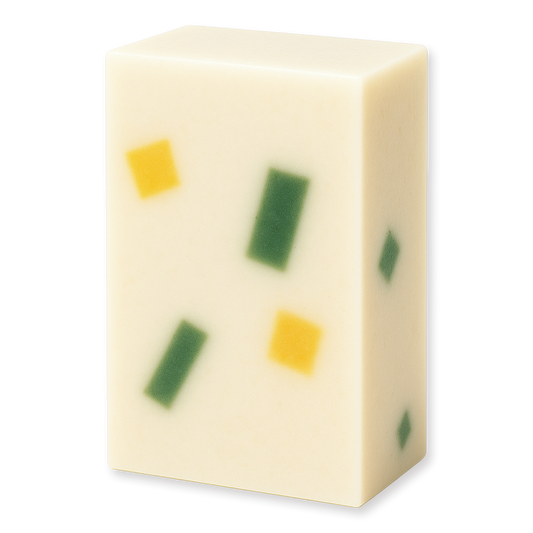 A rectangular bar of creamy off-white soap with embedded green and yellow square pieces, shown on a plain white background.