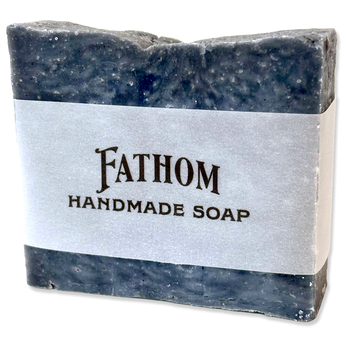 A rectangular bar of Fathom Handmade Soap with a textured dark gray and blue marbled finish, wrapped in a white paper band with black text.