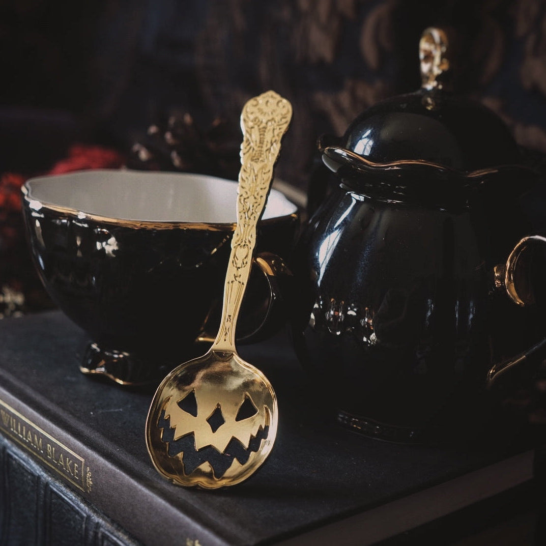 Decorative gold spoon with a black background featuring a bowl and a black container.