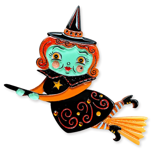 A whimsical witch pin featuring a turquoise face, orange hair, a black hat with orange trim, and a black dress with red swirls, orange accents, and a yellow broom, isolated on a white background.