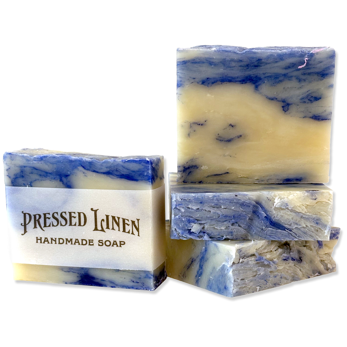Four handmade soap bars with a blue and cream marbled pattern, with one bar wrapped in a paper label that reads 'PRESSED LINEN HANDMADE SOAP'.